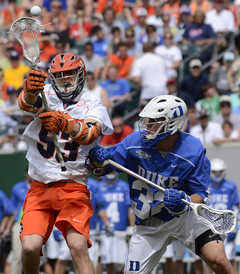 Luke Cometti throws a pass under pressure from a Duke defender.