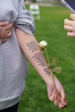 Lindy Melegari pulls up her sleeve to reveal a tattoo of a poem that Frederick “Sandy” Phillips, whom she represents, wrote.