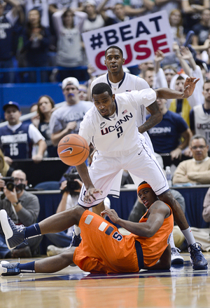 Connecticut forward DeAndre Daniels reaches for a loose as Syracuse small forward C.J. Fair falls between his legs.