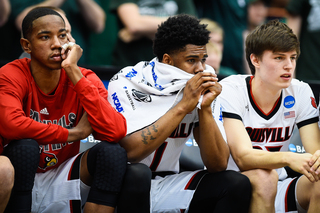 Anton Gill, center, puts a towel over his face as Michigan State secures its victory over the Cardinals.