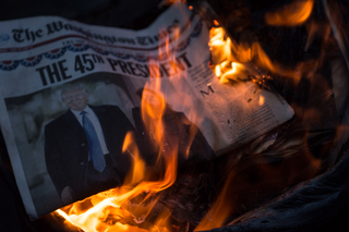 Anti-Trump protesters at Franklin Square light trash cans in the middle of the street using Trump paraphernalia and Friday's edition of The Washington Times.